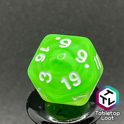 A close up of the D20 from the Ectoplasm 7 piece dice set from Tabletop Loot with swirls of lime green in clear resin and white numbering.