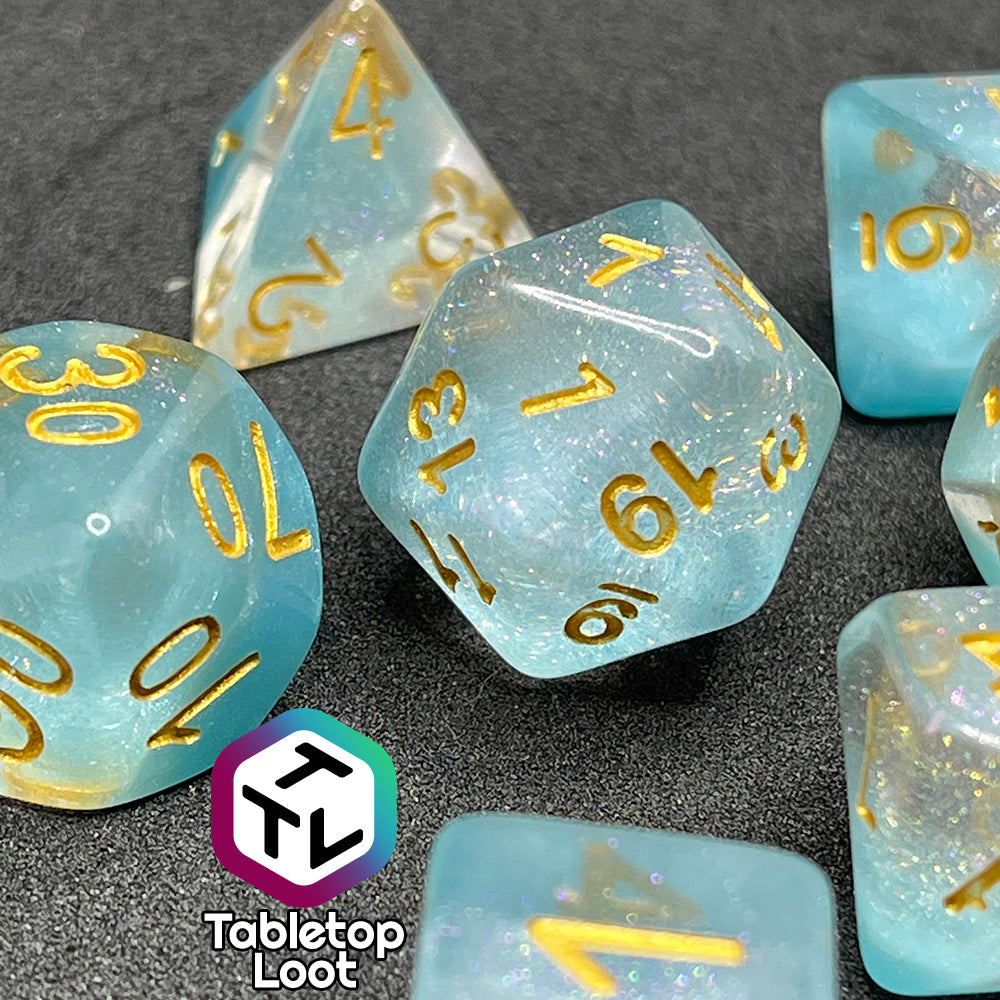 The Elsa 7 piece dice set from Tabletop Loot with a layer of sky blue under glittery clear resin and golden numbering.