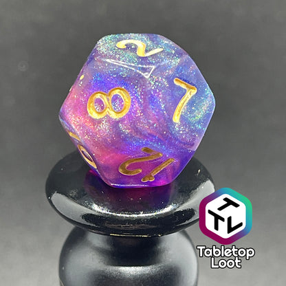A close up of the D12 from the Elvish Magic 7 piece dice set from Tabletop Loot with shimmering swirls of red, pink, and purple in blue with gold numbering.
