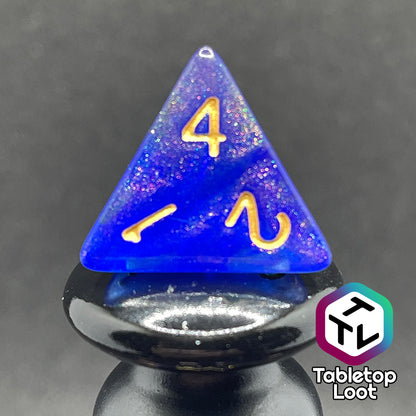 A close up of the D4 from the Elvish Magic 7 piece dice set from Tabletop Loot with shimmering swirls of red, pink, and purple in blue with gold numbering.