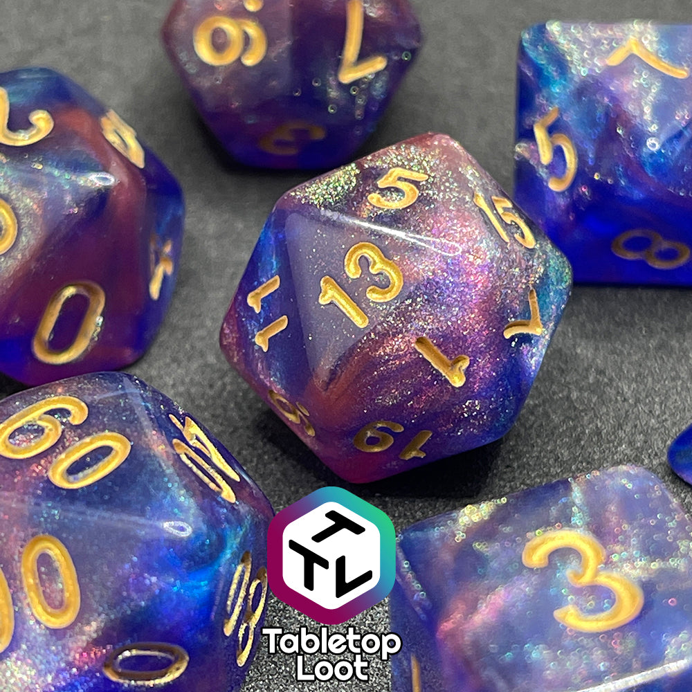 A close up of the Elvish Magic 7 piece dice set from Tabletop Loot with shimmering swirls of red, pink, and purple in blue with gold numbering.