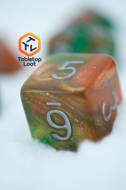 A close up of the D6 from the Emerald Vale 7 piece dice set from Tabletop Loot with swirls of orange in green resin, lots of sparkle, and white numbering.