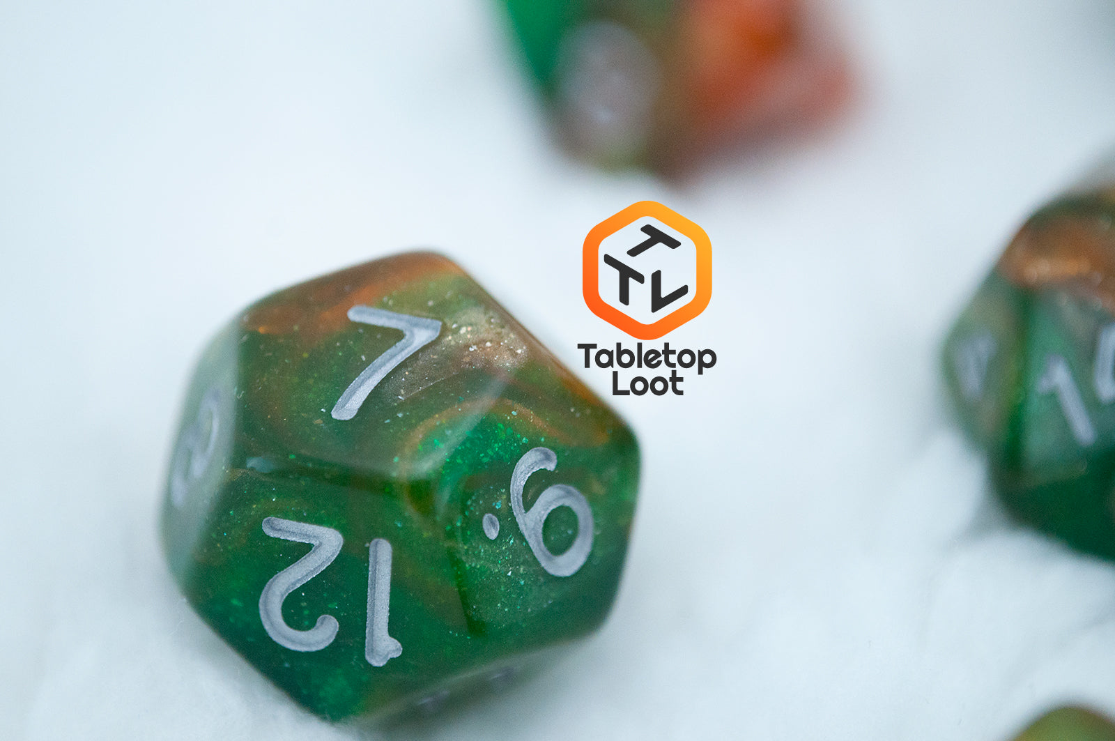 A close up of the D12 from the Emerald Vale 7 piece dice set from Tabletop Loot with swirls of orange in green resin, lots of sparkle, and white numbering.