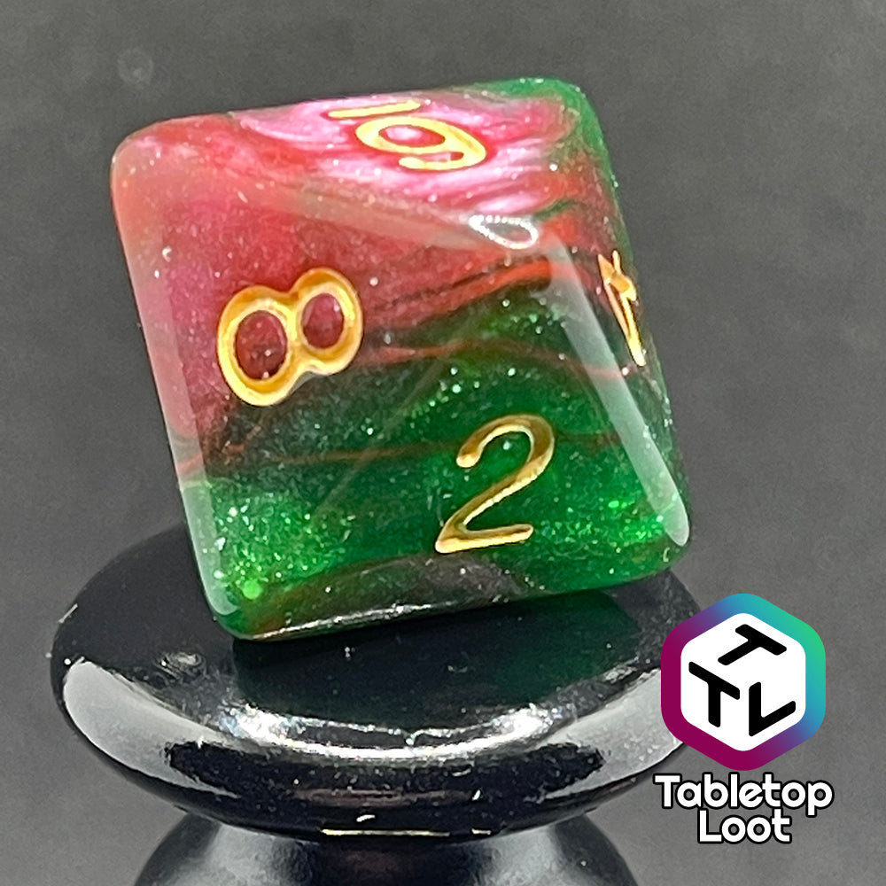 A close up of the D8 from the Enchanted Forest 7 piece dice set from Tabletop Loot with swirls of pink and green glittery resin and gold numbering.