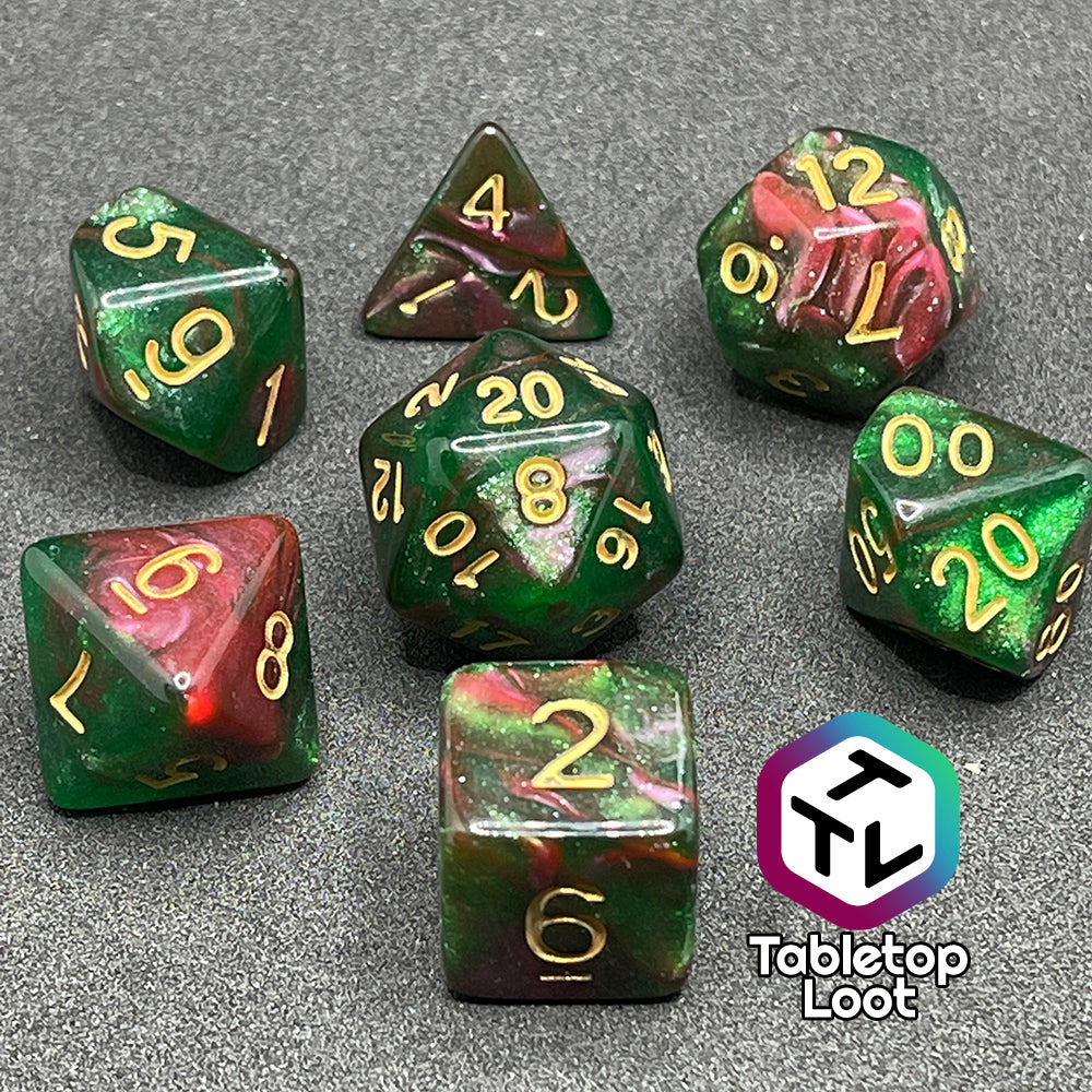 The Enchanted Forest 7 piece dice set from Tabletop Loot with swirls of pink and green glittery resin and gold numbering.