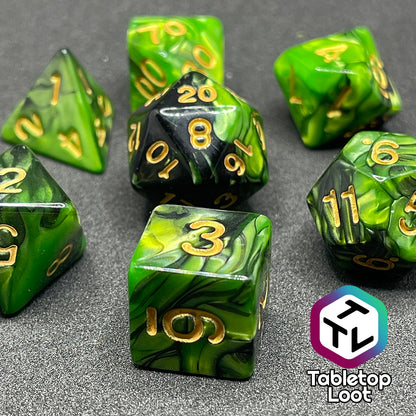 A close up of the Entangle 7 piece dice set from Tabletop Loot with swirls of pearlescent green and black and golden numbering.