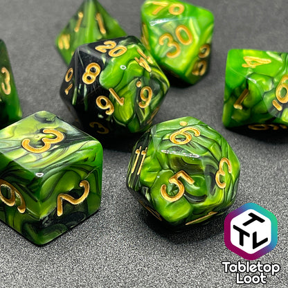 A close up of the D12 and D6 from the Entangle 7 piece dice set from Tabletop Loot with swirls of pearlescent green and black and golden numbering.
