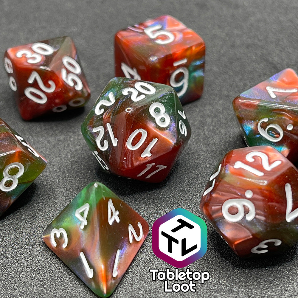 A close up of the Ether Stone 7 piece dice set from Tabletop Loot with glittering and pearlescent swirls of red, green, blue, and golden brown with white numbering.