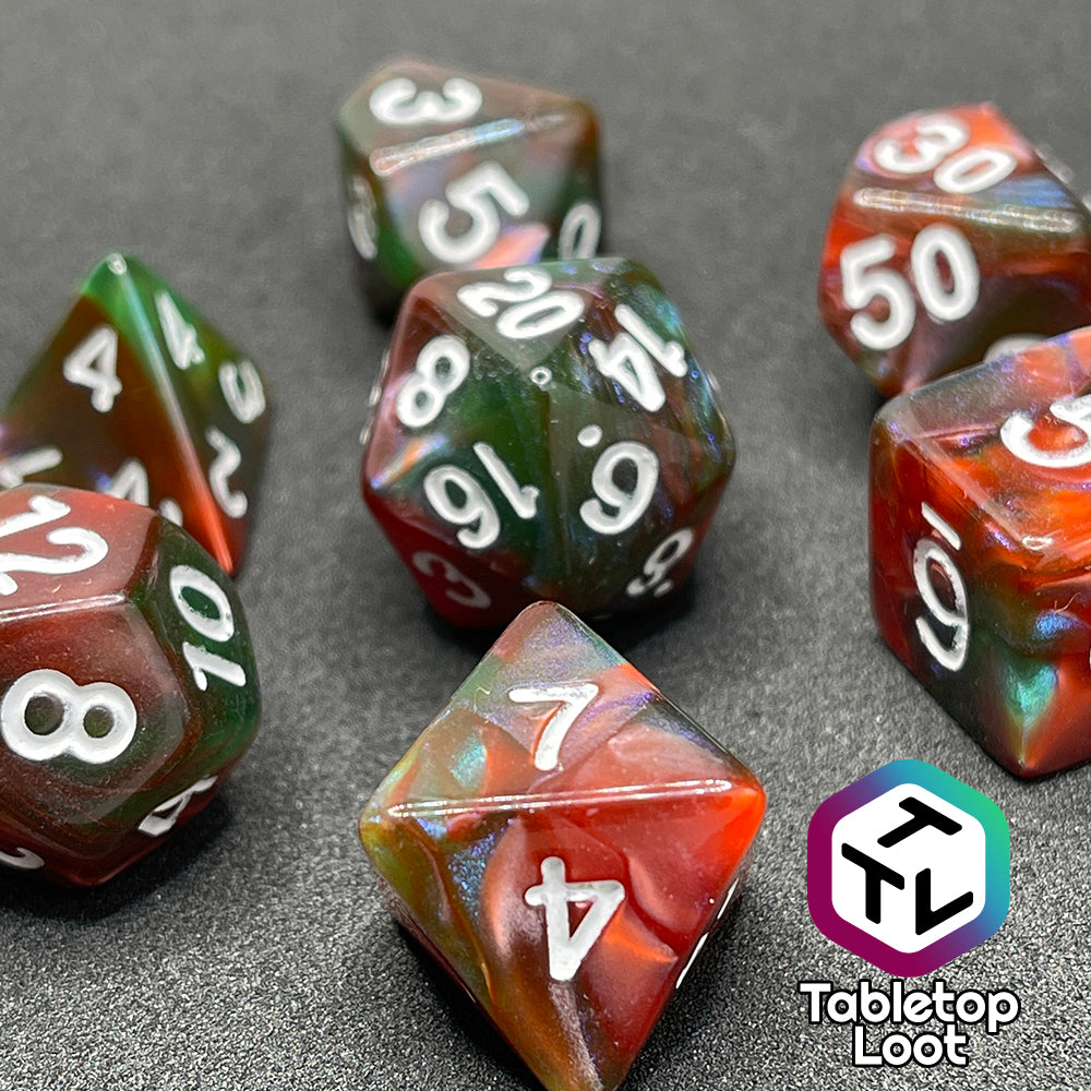 A close up of the Ether Stone 7 piece dice set from Tabletop Loot with glittering and pearlescent swirls of red, green, blue, and golden brown with white numbering.
