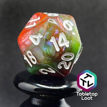 A close up of the D20 from the Ether Stone 7 piece dice set from Tabletop Loot with glittering and pearlescent swirls of red, green, blue, and golden brown with white numbering.