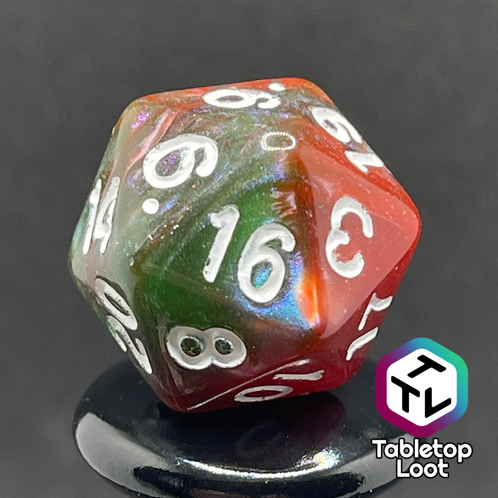 A close up of the D20 from the Ether Stone 7 piece dice set from Tabletop Loot with glittering and pearlescent swirls of red, green, blue, and golden brown with white numbering.