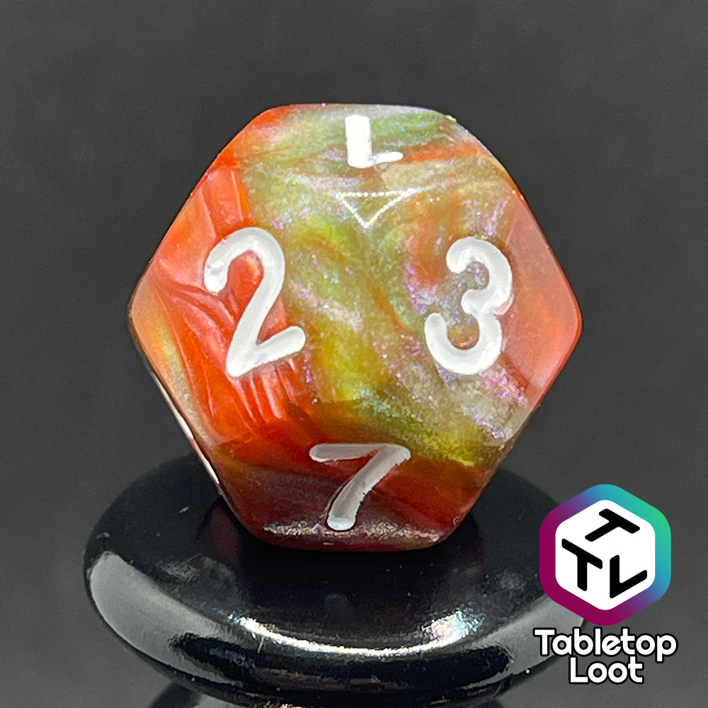 A close up of the D12 from the Ether Stone 7 piece dice set from Tabletop Loot with glittering and pearlescent swirls of red, green, blue, and golden brown with white numbering.