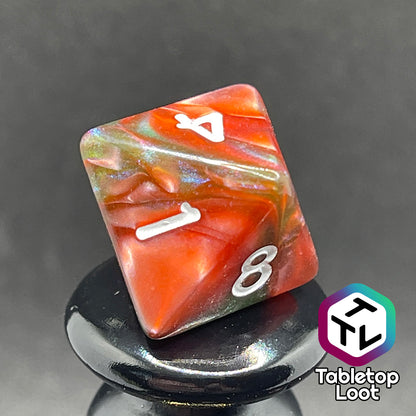A close up of the D8 from the Ether Stone 7 piece dice set from Tabletop Loot with glittering and pearlescent swirls of red, green, blue, and golden brown with white numbering.