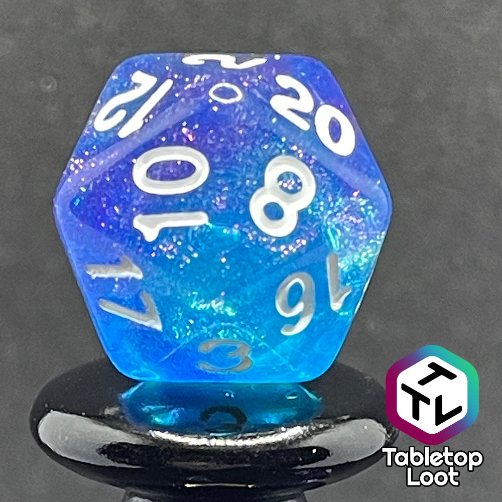 A close up of the D20 from the Fathomless 7 piece dice set from Tabletop Loot with swirls of glitter and purple in deep blue and white numbering.