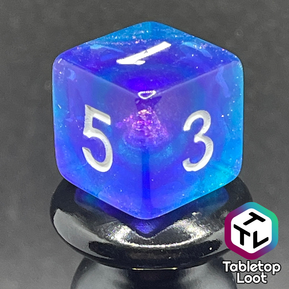 A close up of the D6 from the Fathomless 7 piece dice set from Tabletop Loot with swirls of glitter and purple in deep blue and white numbering.