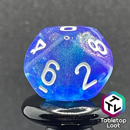 A close up of the D10 from the Fathomless 7 piece dice set from Tabletop Loot with swirls of glitter and purple in deep blue and white numbering.