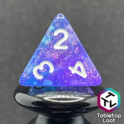 A close up of the D4 from the Fathomless 7 piece dice set from Tabletop Loot with swirls of glitter and purple in deep blue and white numbering.
