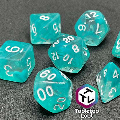 The Feather Fall 7 piece dice set from Tabletop Loot with swirls of teal in clear and white numbering.
