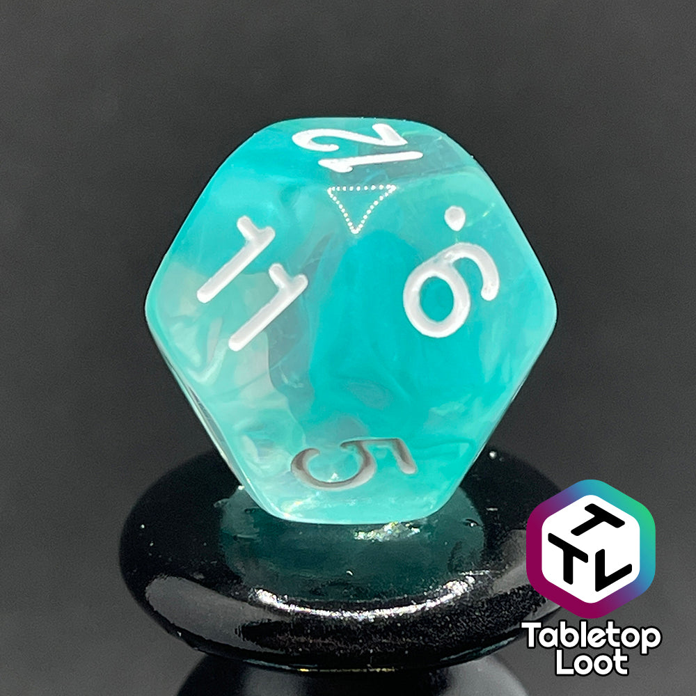 A close up of the D12 from the Feather Fall 7 piece dice set from Tabletop Loot with swirls of teal in clear and white numbering.
