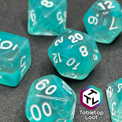 A close up of the Feather Fall 7 piece dice set from Tabletop Loot with swirls of teal in clear and white numbering.
