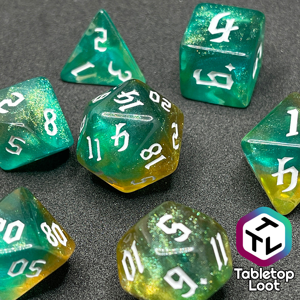 A close up of the Fey Moss 7 piece dice set from Tabletop Loot with swirls of glittery green and yellow and white bold gothic numbering.