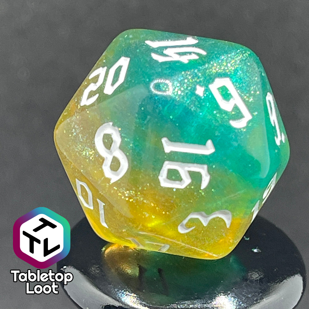 A close up of the D20 from the Fey Moss 7 piece dice set from Tabletop Loot with swirls of glittery green and yellow and white bold gothic numbering.