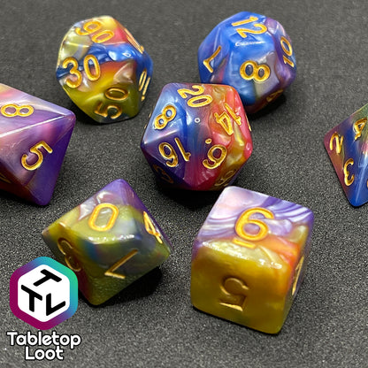 A close up of the Fey and Flowers 7 piece dice set with swirls of pearlescent shades of yellow, purple, red, blue, and green and gold numbering.