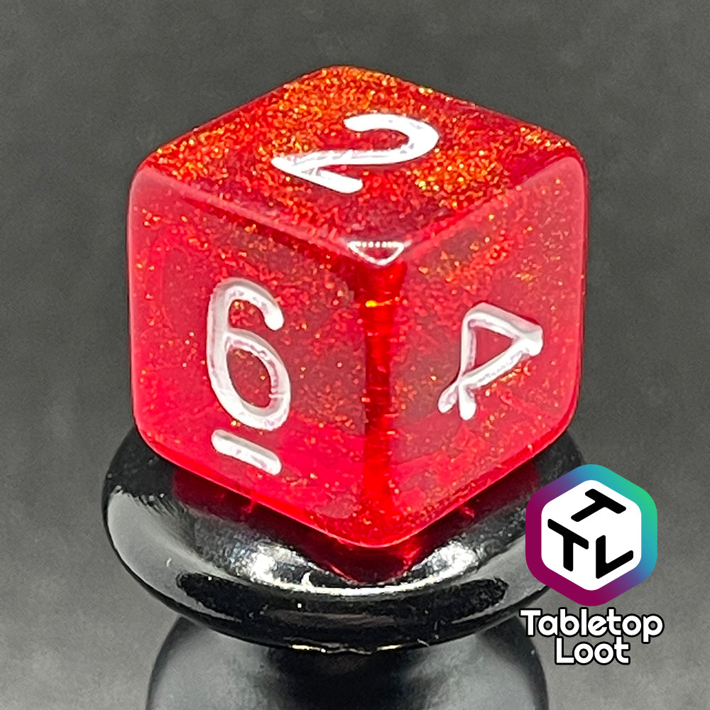 A close up of the D6 from the Fire Genasi 7 piece dice set from Tabletop Loot with swirls of gold micro glitter in red with white numbering.