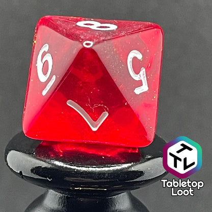 A close up of the D8 from the Fire Genasi 7 piece dice set from Tabletop Loot with swirls of gold micro glitter in red with white numbering.