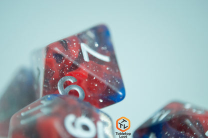 A close up of the D8 from the Fire and Ice 7 piece dice set from Tabletop Loot with swirls of blue and red in a clear glittery resin and silver numbering.