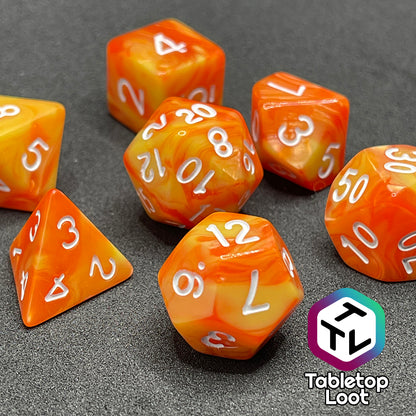 A close up of the Fireball 7 piece dice set from Tabletop Loot, swirling with yellow and orange and inked in white.