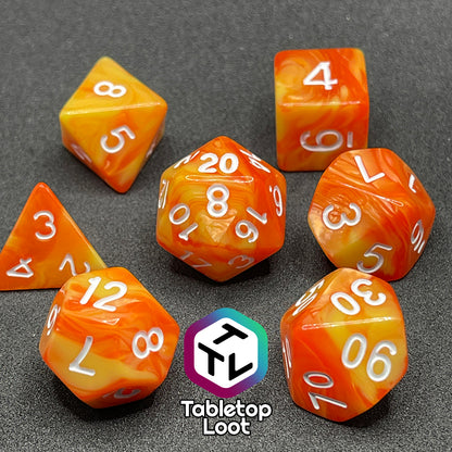 The Fireball 7 piece dice set from Tabletop Loot, swirling with yellow and orange and inked in white.