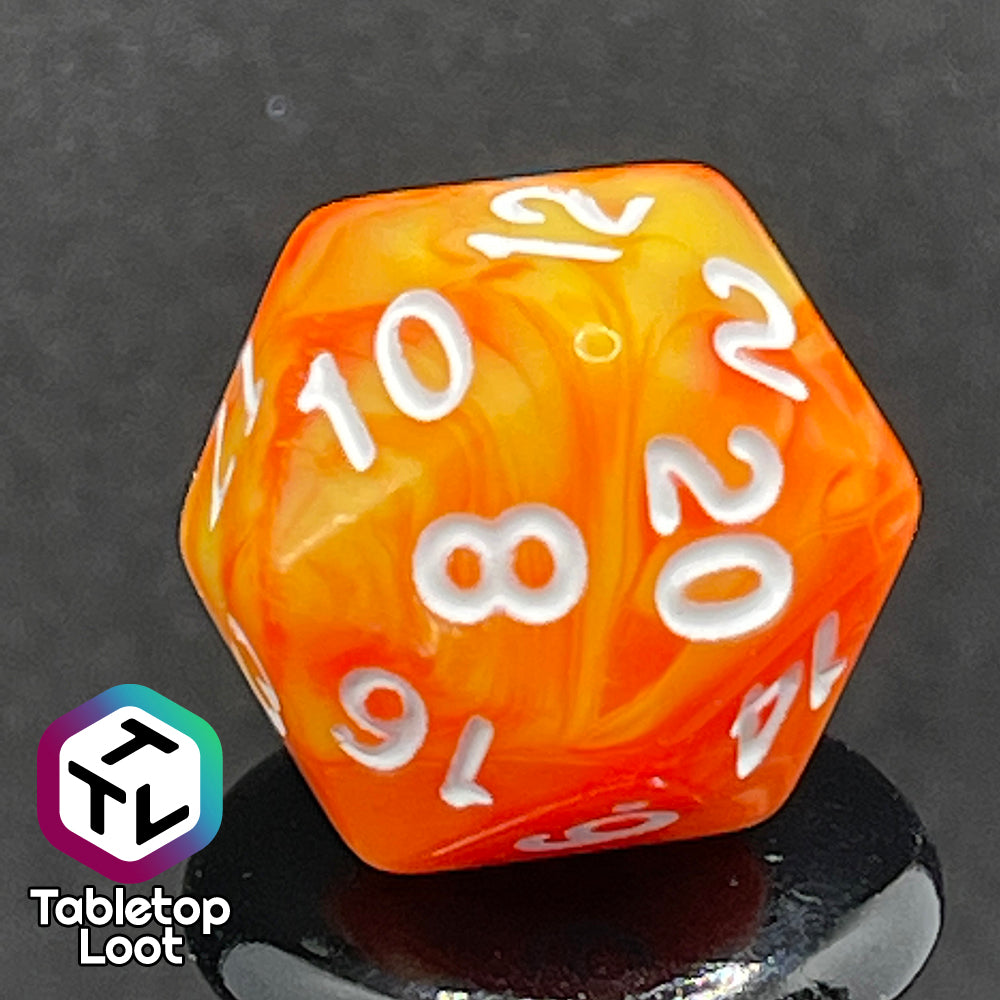 A close up of the D20 from the Fireball 7 piece dice set from Tabletop Loot, swirling with yellow and orange and inked in white.