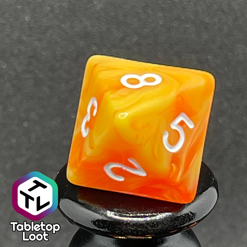 A close up of the D8 from the Fireball 7 piece dice set from Tabletop Loot, swirling with yellow and orange and inked in white.