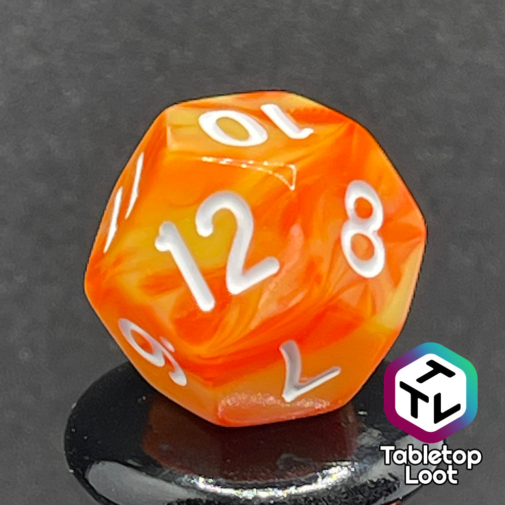 A close up of the D12 from the Fireball 7 piece dice set from Tabletop Loot, swirling with yellow and orange and inked in white.
