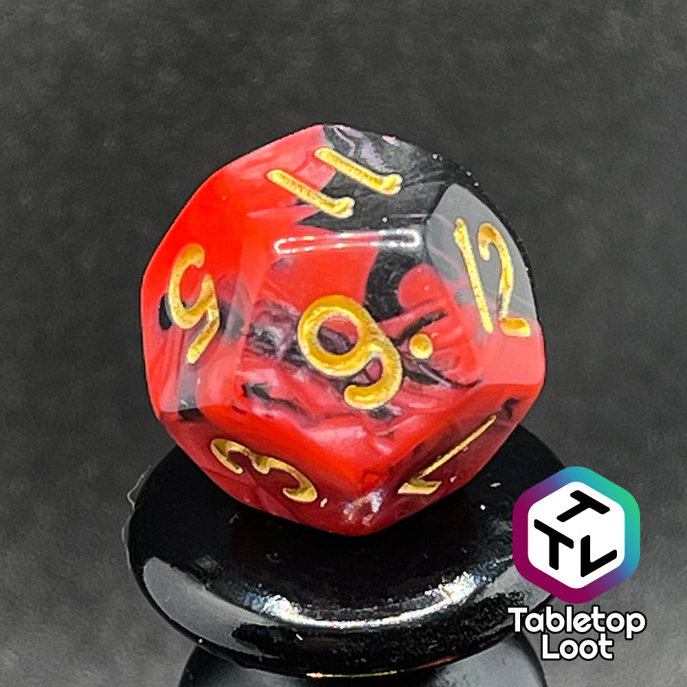 A close up of the D12 from the Forge Embers 7 piece dice set with swirled black and red and gold numbering.
