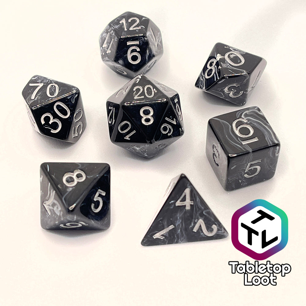The Form of Dread 7 piece dice set from Tabletop Loot with swirls of white in black resin and silver numbering.