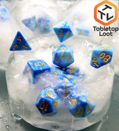 The Frost Giant 7 piece dice set from Tabletop Loot with swirls of light and dark blue resin and gold numbering.