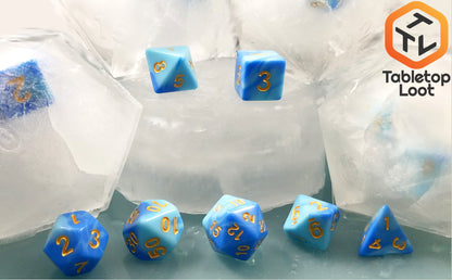 The Frost Giant 7 piece dice set from Tabletop Loot with swirls of light and dark blue resin and gold numbering.