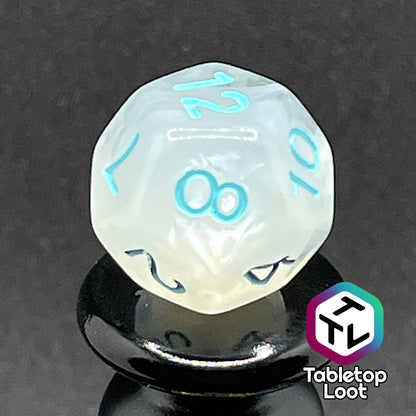 A close up of the D12 from the Frostmaiden 7 piece dice set from Tabletop Loot with swirls of frosty white in clear resin and blue numbering.