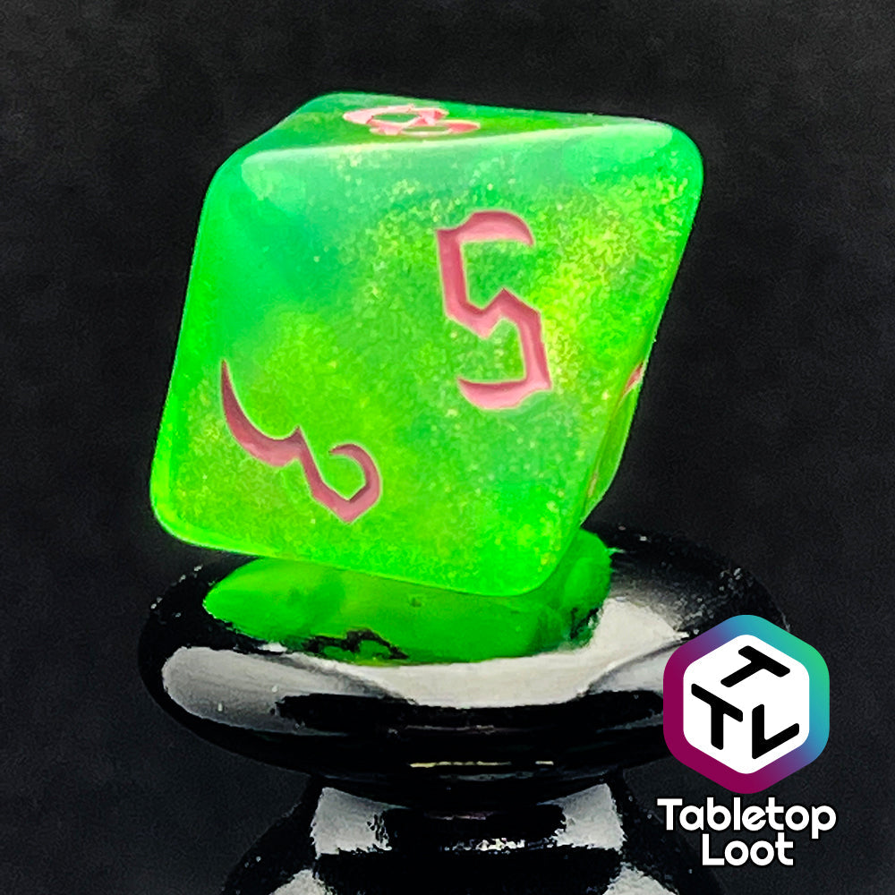 A close up of the D8 from the Sour Apple 7 piece dice set from Tabletop Loot; shimmery green dice with pink gothic numbering.
