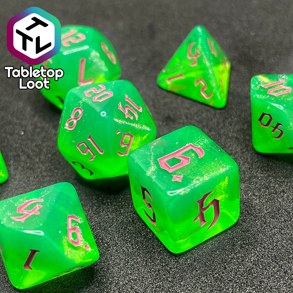 A close up of the Sour Apple 7 piece dice set from Tabletop Loot; shimmery green dice with pink gothic numbering.