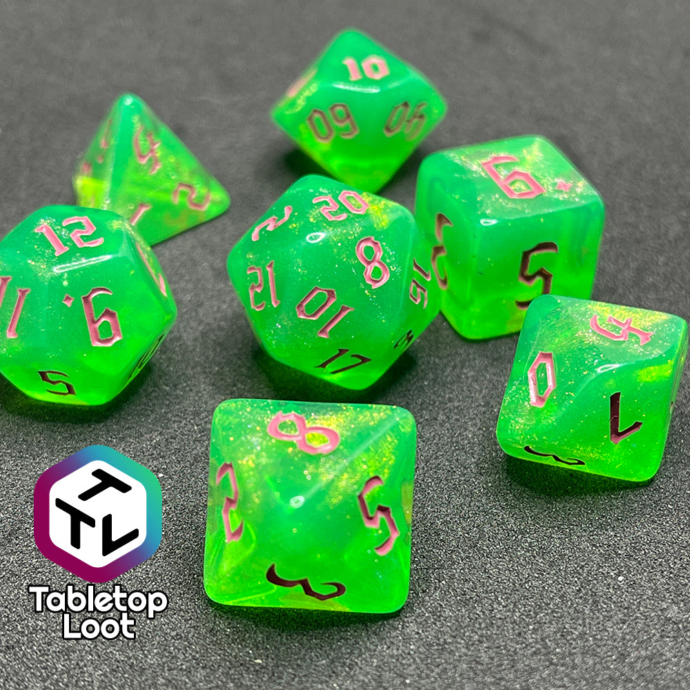 A close up of the Sour Apple 7 piece dice set from Tabletop Loot; shimmery green dice with pink gothic numbering.