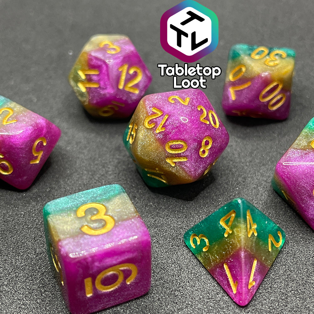 A close up of the Gem of Brightness 7 piece dice set from Tabletop Loot with stripes of glittery pink, gold, and green and inked in gold.
