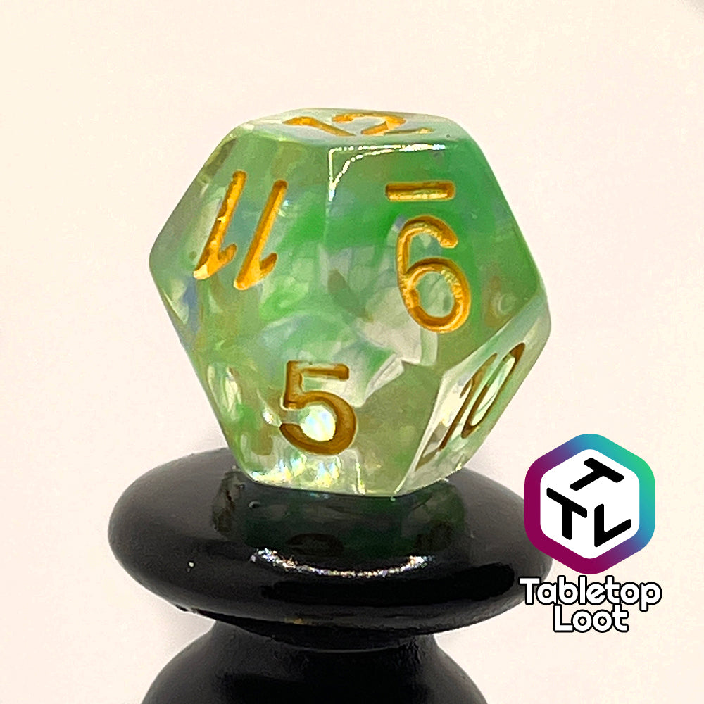 A close up of the D12 from the Gentle Repose 7 piece dice set with swirls of bright green and blue in clear resin and gold numbering.