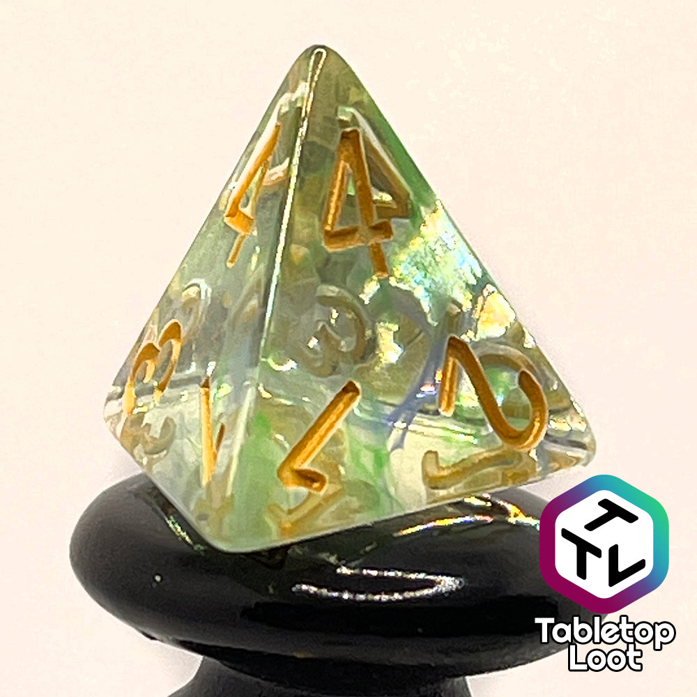 A close up of the D4 from the Gentle Repose 7 piece dice set with swirls of bright green and blue in clear resin and gold numbering.
