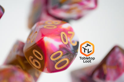 A close up of the percentile die from the GoodBerries 7 piece dice set from Tabletop Loot with swirls of red, brown, black, and white and gold numbering.