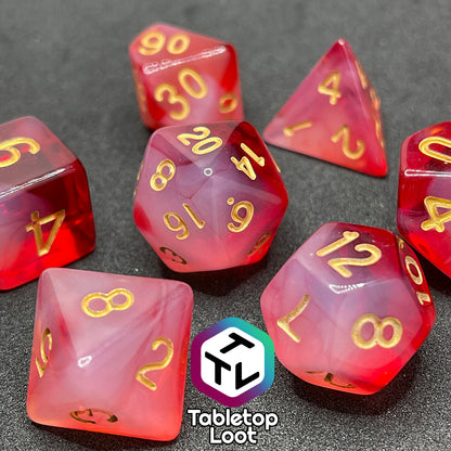 The Healing Word 7 piece dice set from Tabletop Loot with swirls of white in red and gold numbering.