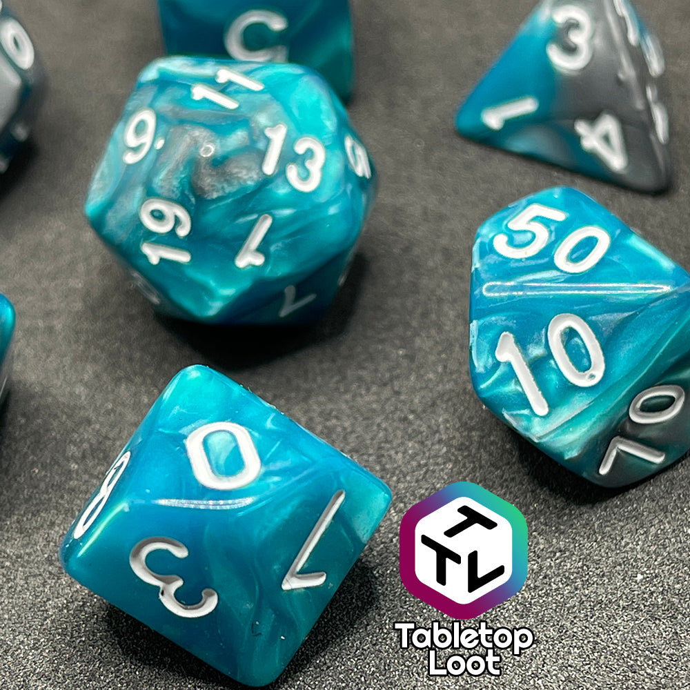 A close up of the D10 and percentile die from the Hunter's Mark 7 piece dice set from Tabletop Loot with pearlescent swirls of blue and silver and white numbering.