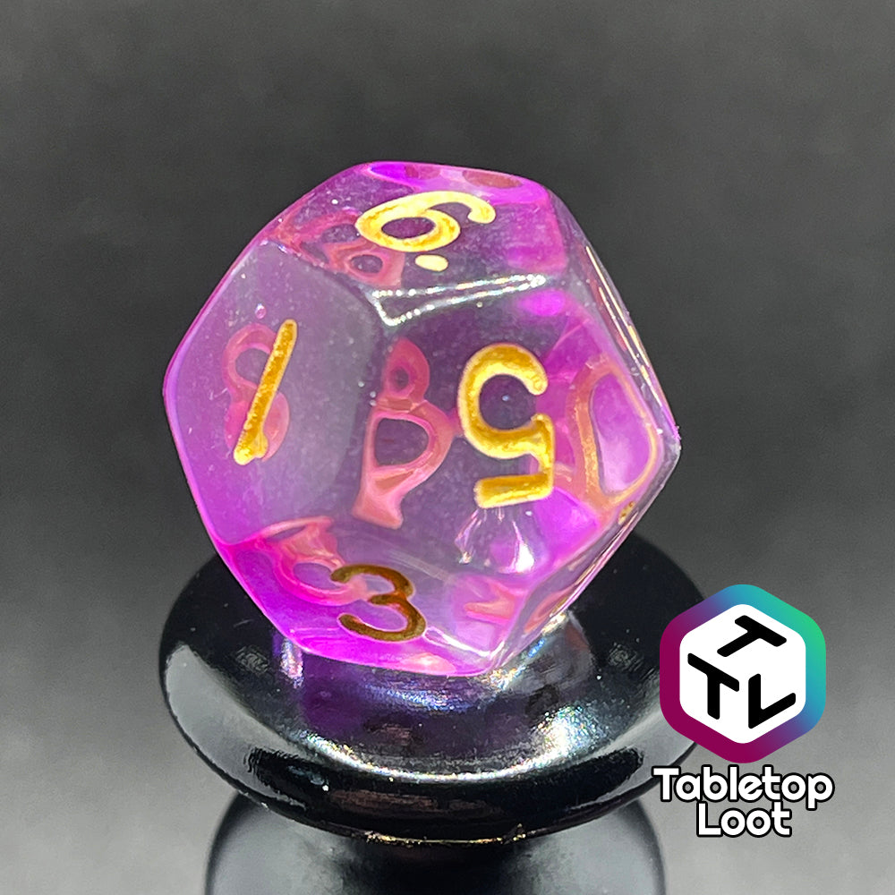 A close up of the D12 from the Incantation 7 piece dice set from Tabletop Loot with swirls of fuchsia in clear and gold numbering.